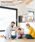 Amazon Echo-style smart speaker on a shelf in a bright living room with a family and a child playing.