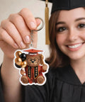 Graduate holding Personalized Graduation Bear Keychain For The Grad Custom Name And Class Year Keepsake Cute Senior Design Gift For Class Of 2026 Unique Gift Idea For The Graduate And Their Big Milestone