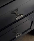Six Pack Brushed Nickel Triangular Cabinet Knobs With Open Center Design for modern cabinets and drawers, shown installed on black drawer.