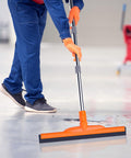 Person using Heavy-Duty Floor Squeegee With 62-Inch Adjustable Handle And EVA Foam Blade on concrete surface cleanup