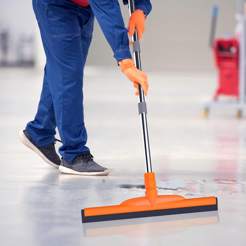 Person using Heavy-Duty Floor Squeegee With 62-Inch Adjustable Handle And EVA Foam Blade on concrete surface cleanup