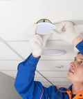 Installer placing a 5 Pack White Fire Sprinkler Concealed Covers with Rustproof Replaceable Convex Trim Rings on ceiling.