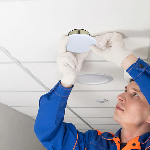 Installer placing a 5 Pack White Fire Sprinkler Concealed Covers with Rustproof Replaceable Convex Trim Rings on ceiling.