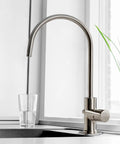Premium Heavy Duty Reverse Osmosis Faucet For Kitchen Sink with brushed nickel finish, flexibly shaped spout, and glass of water.