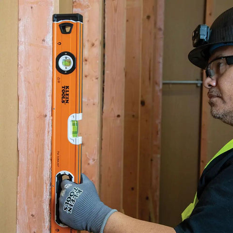935L 24-Inch Magnetic Bubble Level with Adjustable Vial used by worker for wood alignment, high visibility orange, rubberized end caps