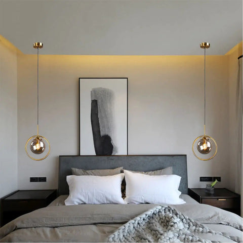 Bedroom with two Dope Smoke Gray Glass Globe Pendant Lights With Gold Rim above nightstands.