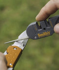Person using dual stage knife sharpener with preset carbide and ceramic slots for camping gear and pocket knives.