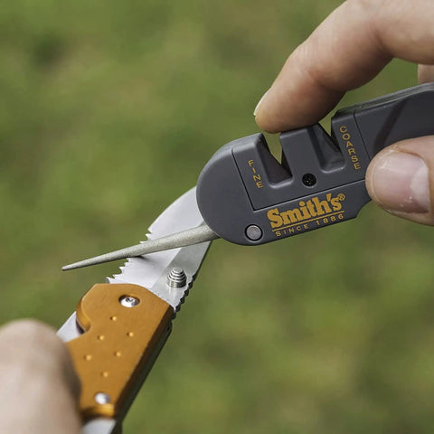Person using dual stage knife sharpener with preset carbide and ceramic slots for camping gear and pocket knives.