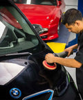 Person using Hex-Logic Quantum Buffing Pad Sampler Kit Four Pad Set for Pro Polishing on car hood in garage.