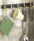 Sturdy Steel Wall Mounted Coat Rack Cool Fix For Your Hallway Or Living Room Easily Park Your Outerwear Totes And Keys To Keep Your Pad Spotless With Super Easy Everyday Storage hanging mugs and utensils on a sleek black and gold rack.