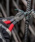 D201-7CSTA Linesman Pliers With Spring Loaded Action cutting rebar tie wire, showcasing kickass grip and aggressive knurl.