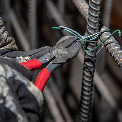 D201-7CSTA Linesman Pliers With Spring Loaded Action cutting rebar tie wire, showcasing kickass grip and aggressive knurl.