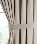 Close-up of Two XXL Wall To Wall Beige Ivory Blackout Curtains Panels, 108 By 108 Inches Each, tied back for an elegant look.