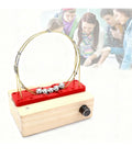Hands On Perpetual Motion Science Kit With Electromagnetic Cyclotron And Iron Ball Circular Motion Demonstrator Magnetic Drive Tech For STEM Education Red Color Edition on wooden base, students observing in background.