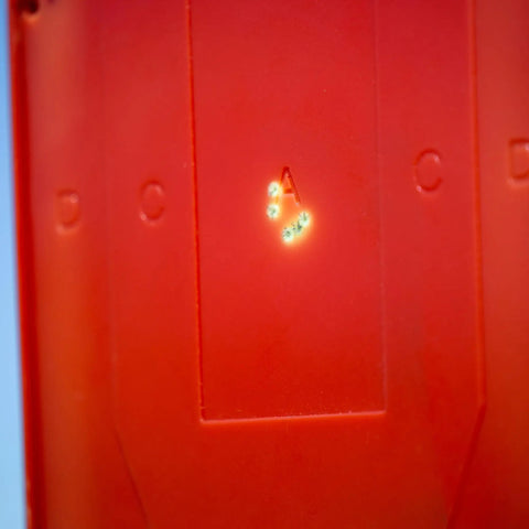 Close-up of Half Size Self Healing Silhouette Reactive Shooting Target with hit marks on red polymer surface.
