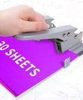 Hand using 2 Hole Punch for Paper, Adjustable Heavy Duty Metal Hole Puncher With Locking Handle, 30 Sheet Capacity, on purple paper