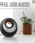 Minimalist USB-C Desktop Speakers With Bluetooth 5.0, 8W RMS, single speaker on a desk next to a plant and laptop, sleek black finish.