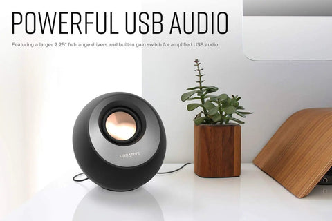Minimalist USB-C Desktop Speakers With Bluetooth 5.0, 8W RMS, single speaker on a desk next to a plant and laptop, sleek black finish.