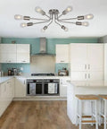 Mid Century 8 Light Chandelier in Brushed Nickel in modern kitchen with white cabinets and wood flooring.