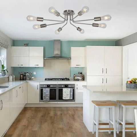 Mid Century 8 Light Chandelier in Brushed Nickel in modern kitchen with white cabinets and wood flooring.