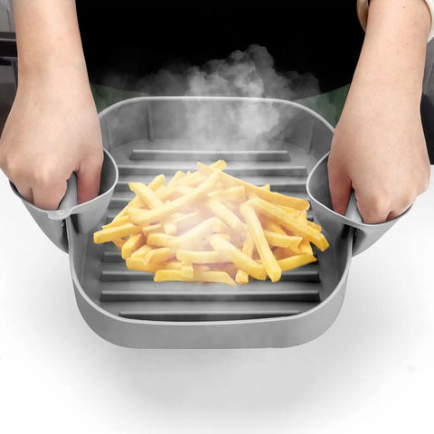 Person holding Air Fryer Silicone Pot 8.1 Inch Basket Pan with dual handles and fries inside, steam visible, grey color