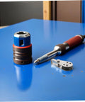 Workshop tools including a screwdriver, a rotary saw blade and a metal attachment on a blue workbench surface. Modern tool collection for DIY projects.