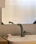 Bathroom sink area with mirror and visible black plastic corner protectors, anti-collision cushioned edge guards, no slip.