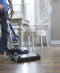 Person using a vacuum cleaner on wooden floor in a home setting