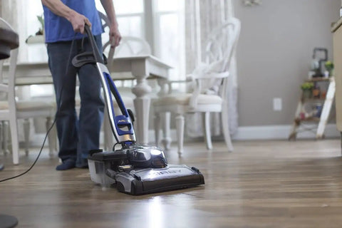 Person using a vacuum cleaner on wooden floor in a home setting