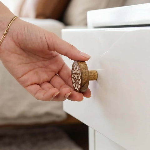 Hand placing Boho Bulk Wooden Drawer Knobs Set With 300 Pieces on white cabinet, showing brown floral round design.