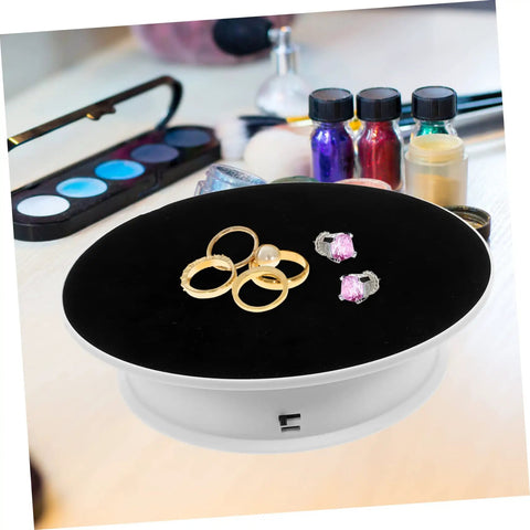 Rotating Electric Turntable Display Stand With Smooth Motorized Motion showcasing rings and earrings on a black velvet surface.