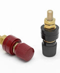Beefy One Quarter Inch Remote Battery Terminal Stud Pair Featuring Pure Copper Build And Bakelite Shielding For High Amp Draws and Zero Hassle Wiring up your Engine Bay or Hot Rod Build Today - red and black terminals with gold connectors.