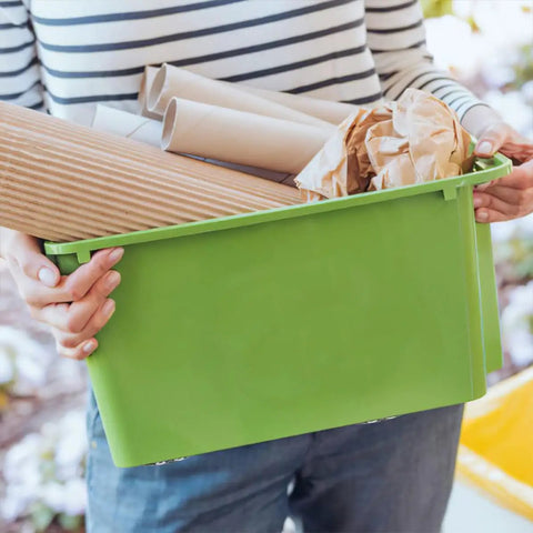 Person holding a green storage bin with paper, showcasing use of 6 Pack Stick-On Adhesive Mini Swivel Caster Wheels For Furniture And Appliances