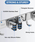 Close-up of stainless steel wall mounted broom and mop holder with five racks and four hooks, self-adhesive, heavy duty.