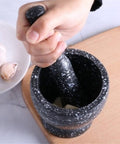 Hand using Heavy Duty Unpolished Granite Mortar And Pestle Set For Home Kitchen Grinds Guacamole Salsa Spices And Nuts Like A Pro