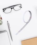 Six Pack Adhesive Flexible Tape Measures Set, 1m And 2m Lengths, shown with glasses and stationery on a desk