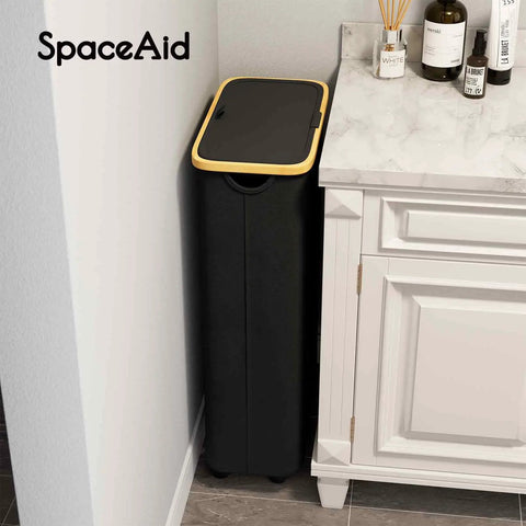 Slim Laundry Hamper With Wheels And Lid, 62L Rolling Clothes Basket With Bamboo Handle next to a bathroom cabinet, black