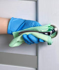 Person wearing Top Notch Disposable Vinyl Exam Gloves In Steel Blue, Cast At Four Mil Thick, cleaning door handle.