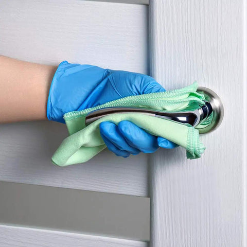 Person wearing Top Notch Disposable Vinyl Exam Gloves In Steel Blue, Cast At Four Mil Thick, cleaning door handle.