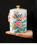 Premium Vintage Enamel Ceramic Tea Storage Jar Airtight Large Capacity Dry Food Canister For Coffee Beans Spices Nuts And Loose Leaf Tea in hand, decorated with flowers and birds.