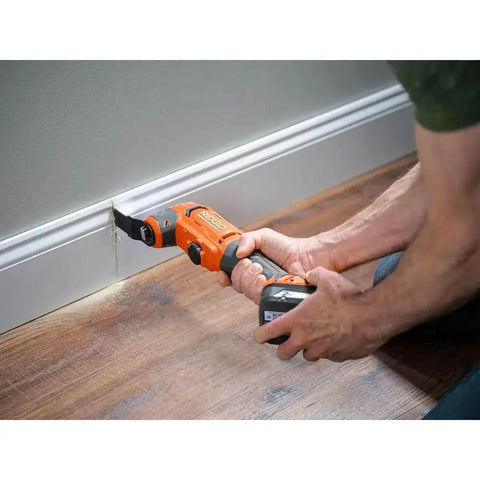 Person using 18V Cordless Oscillating Multi Tool Kit With Two 2.0Ah Batteries And Charger Quick Change System on baseboard.
