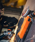 Magnetic Grinder Grip Accessory attached to grinder on ferrous surface during metal fabrication, with sparks flying.