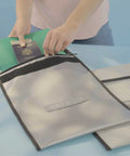 Person placing passport and documents in Fireproof Bug Out Backpack For Docs And Tech, 20L Water-Resistant Go Bag That Withstands 1832 Fahrenheit