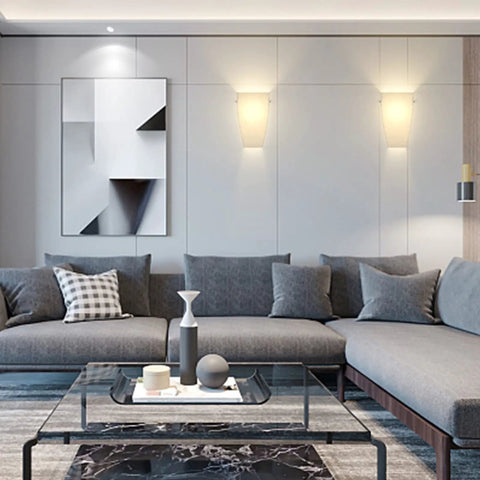 Modern living room with Dope Wall Sconces Set Of Two, acrylic shades, mounted on a wall above a grey sectional sofa with decorative cushions.