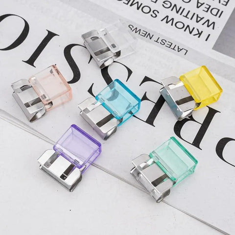 20 Pairs Quick Fix Hem Clips and Reusable Clamps for Pants, transparent purple tops with sturdy metal base laid out on paper