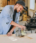 Man using router on wood with Halloween skull template, focusing on detailed carving for his DIY craft project.