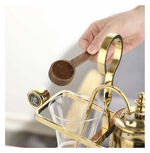 Top Shelf Siphon Coffee Maker Syphon Glass Brewer 4 Cup with hand holding wooden scoop of coffee grounds.