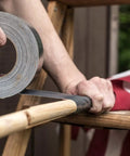 Applying Ferociously Strong Duct Tape 105 Yards Triple Pack Gunmetal Gray for indoor outdoor repairs on wooden surface.