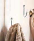 Thirty Pack Mini Iron Wall Hooks With Classic Silver Finish holding a towel on a bathroom wall for easy access.