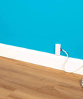 Ultra Flat Adhesive Speaker Wire 16 AWG 2 Conductor, 50 Ft White Spool, Ghost Wire 2.0 installed along blue wall with outlet